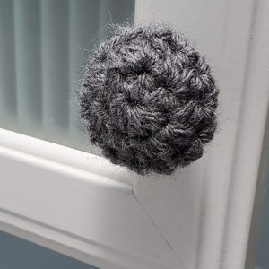 May include: A gray crocheted knob for a cabinet or drawer.