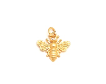 Peut inclure: Un pendentif en forme d'abeille de couleur dorée avec des ailes texturées et un corps segmenté. Ce bijou insecte comporte deux petits accents circulaires transparents sur la tête et un anneau de jonction fixé au sommet pour l'attacher.