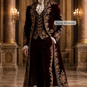 May include: A deep burgundy velvet tailcoat and matching trousers featuring intricate gold floral embroidery. The ensemble includes a vest with gold buttons, a white ruffled cravat with a central jewel, and white ruffled cuffs. Text reads Royal Western.