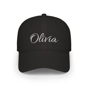 May include: A black baseball cap featuring the name Olivia embroidered in white cursive script across the front centre. The cap has a structured crown, a curved brim, and a button at the top, showcasing a clean and simple design.