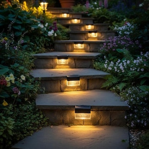 May include: A series of rectangular solar-powered step lights with black frames and clear, textured glass panels. Each light emits a warm, golden glow, mounted onto the vertical risers of a stone staircase surrounded by lush garden foliage.