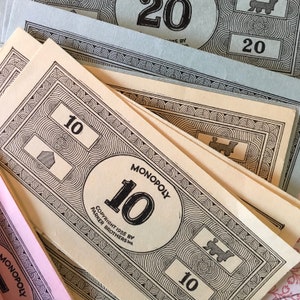 May include: A collection of vintage Monopoly paper money in various denominations including 10 and 20. The bills feature black ink printing on cream, light blue, and pink paper, displaying the Monopoly logo, the number 10, and copyright 1935.