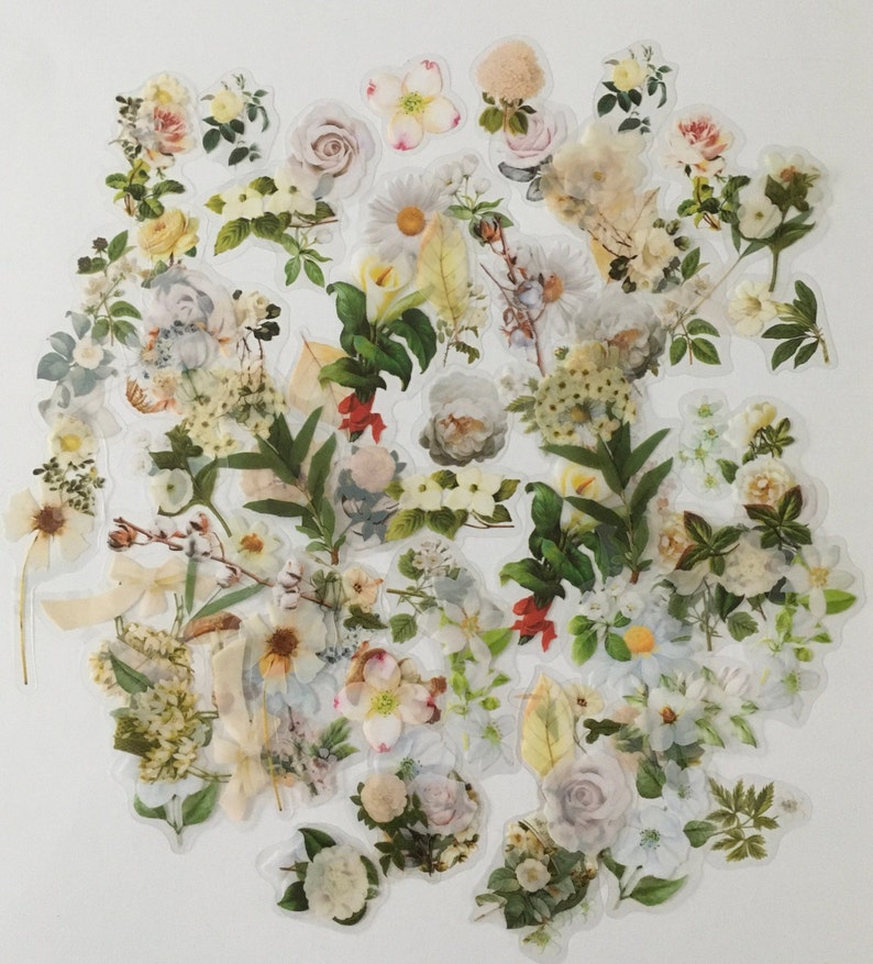以下が含まれることがあります： 緑の葉が付いた白とクリーム色の花のステッカーのコレクション。ステッカーはクラスター状に配置されており、バラ、デイジー、ユリなど、さまざまな種類の花が特徴です。
