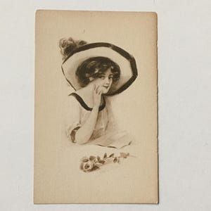 May include: A vintage postcard featuring a black and white illustration of a woman wearing a large, wide-brimmed hat with a black ribbon. She is holding a rose in her hand.