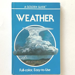 May include: A Golden Guide book titled "Weather" with a blue cover. The cover features a circular illustration of a storm cloud with lightning and rain over a landscape. The text "Full-color, Easy-to-Use" is printed at the bottom.
