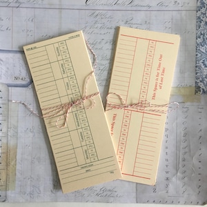 May include: A set of vintage-style time cards with red and white string tied around them. The cards are cream colored with black text and red lines. The text on the cards reads "This Space is for Time Out of Lost Time" and "This Space for". The cards are numbered and have days of the week listed.