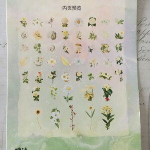 以下が含まれることがあります： 白い紙に様々な花のステッカーが貼られています。ステッカーはグリッド状に配置されており、バラ、デイジー、ユリなど、様々な種類の花が描かれています。紙は薄い緑色の背景で、水彩画のような効果が施されています。