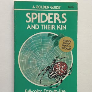 May include: A paperback book titled A GOLDEN GUIDE SPIDERS AND THEIR KIN with a green cover. The cover features a white spider web illustration, a red and white patterned spider, and a gold circular sticker that reads GOLDEN GUIDE PROOF OF PURCHASE.