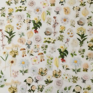 以下が含まれることがあります： 白い紙に様々な花のステッカーが貼られています。ステッカーには、バラ、デイジー、ユリなど、様々な花が描かれています。ステッカーの色は、白、ピンク、黄色、緑など様々です。