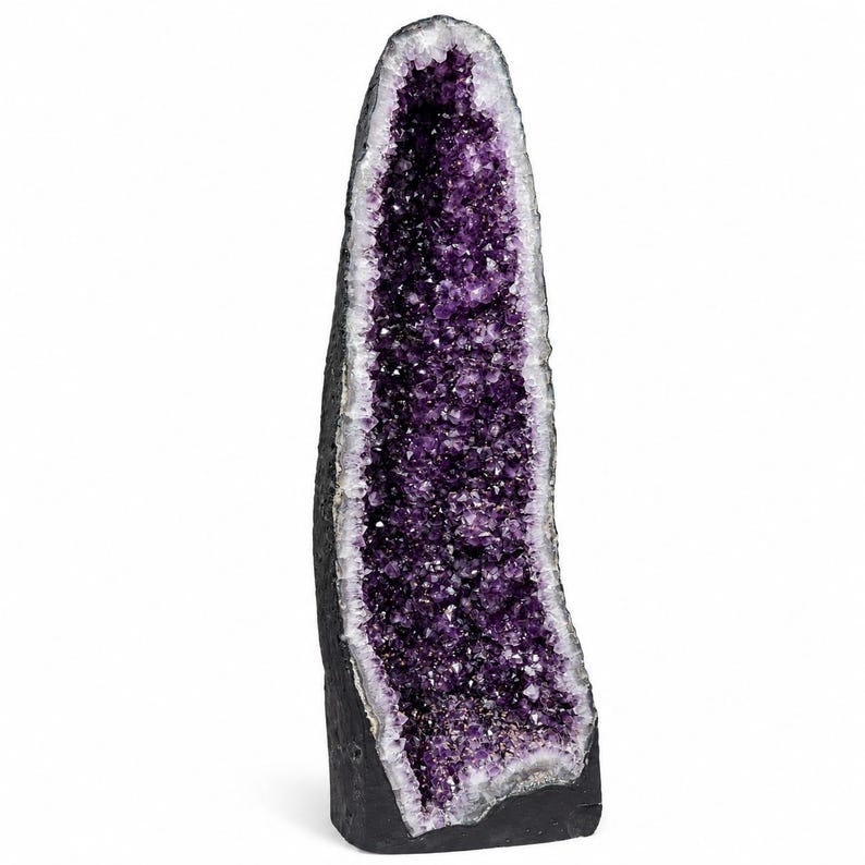 May include: A tall, vertical amethyst geode featuring a deep purple, crystalline interior cavity surrounded by a thick, dark gray, and textured rocky outer shell. The crystal formation tapers toward the top, showcasing natural jagged edges.
