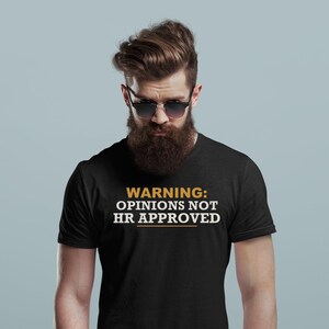 May include: A black short-sleeved t-shirt featuring the text WARNING: OPINIONS NOT HR APPROVED printed in white and yellow. The shirt has a crew neckline and a standard fit, displaying the bold graphic text clearly across the chest area.