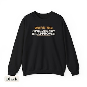 May include: A black long-sleeve crewneck sweatshirt featuring the text "WARNING: OPINIONS NOT HR APPROVED" printed in white and gold. The word "WARNING:" and a horizontal line underneath the text are in gold, while the rest is in white.