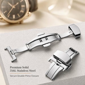Pode incluir: Um fecho de relógio desdobrável em aço inoxidável prateado com um mecanismo de fecho de pressão dupla. A peça metálica é apresentada em posição aberta e fechada, com o texto Premium Solid 316L Stainless Steel.