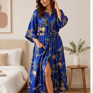 May include: A vibrant blue robe featuring a repeating pattern of cheetahs and tropical foliage. This long-sleeved garment includes a matching tie belt at the waist, a shawl collar, and a single patch pocket on the front, finished with white piping.