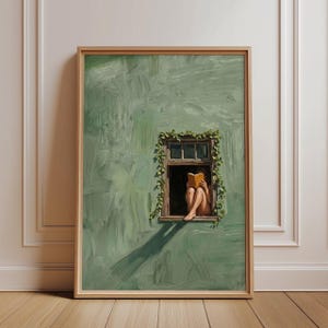 Könnte beinhalten: Ein gerahmter Wandkunstdruck mit einer strukturierten, salbeigrünen Wand und einem dunklen Holzfensterrahmen. Grüne Efeuranken wachsen um das Fenster, in dem eine Figur sitzt und ein offenes gelbes Buch liest. Das Bild ist in einem hellen Holzrahmen.