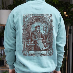 May include: A light blue hoodie featuring a dark brown graphic on the back. The design depicts a person in historical robes holding an hourglass and a scroll, framed by gothic arches and gears. Text reads ARCHITECTURA SYSTEMATIS and MASTER OF BACKGROUND CYCLES MDXVII.