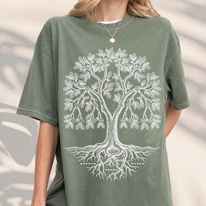 May include: A sage green short-sleeve t-shirt featuring a white line art graphic of an oak tree. The tree branches contain circular nodes with the numbers 3, 5, 7, 10, 12, 13, 14, 15, 18, 20, 22, 25, 28, 30, and 35. The roots include Morse code.