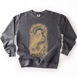 Dark grey dark academia shirt featuring a old gold Opus Magnum raven graphic designed for software engineers.