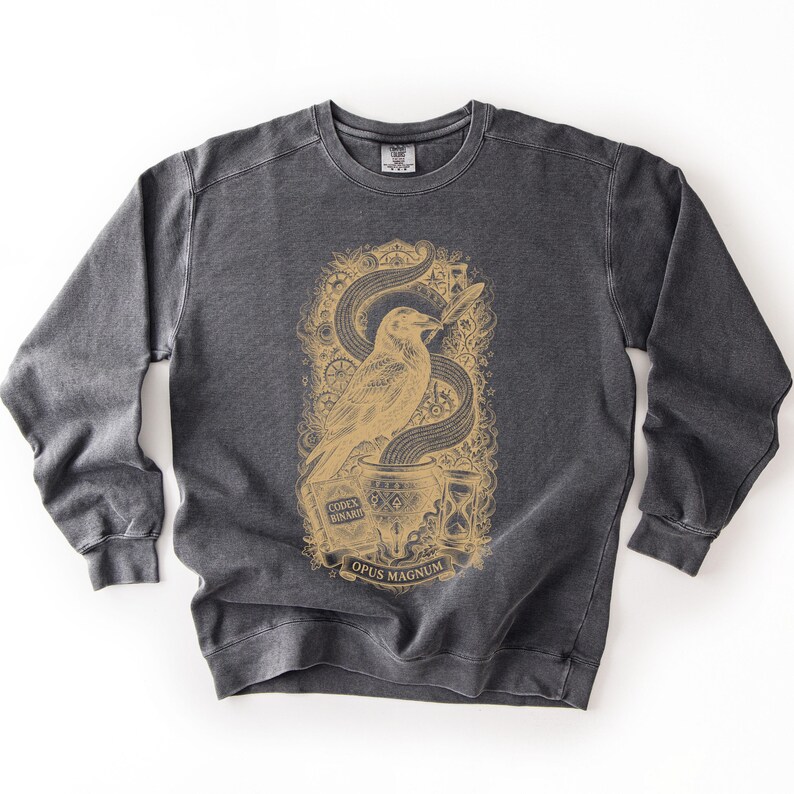 Dark grey dark academia shirt featuring a old gold Opus Magnum raven graphic designed for software engineers.