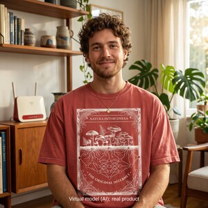 Male virtual model wearing a terracotta red vintage t-shirt with a white "Natura Interconexa" mushroom mycelium network and math nodes graphic. Cozy indoor plant and bookshelf background.
