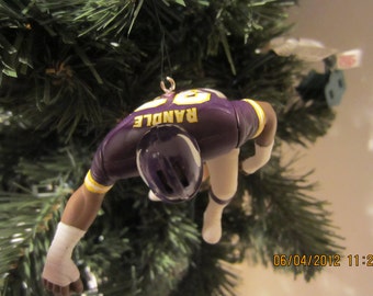 May include: Purple and gold football ornament of a player in a football uniform with the name "RANDLE" on the back.