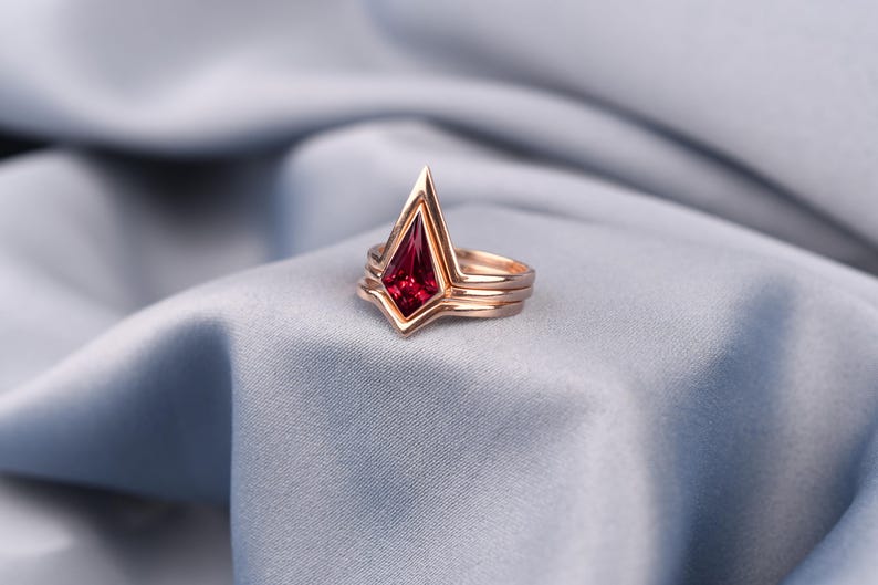 Close-up of faceted red ruby center stone surrounded by layered rose gold plated bands, unique ruby engagement ring