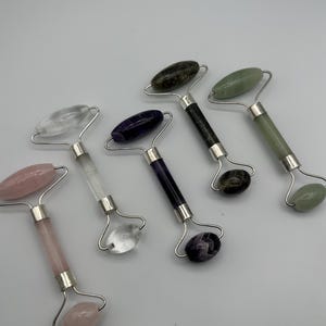 Peut inclure: Cinq rouleaux pour le visage avec des montures en métal argenté et des pierres de différentes couleurs, notamment rose clair, transparent, violet foncé, gris chiné foncé et vert pâle. Chaque outil possède un grand rouleau et un plus petit.
