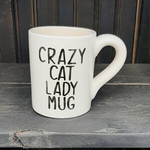 May include: White ceramic mug with black lettering that reads "Crazy Cat Lady Mug".
