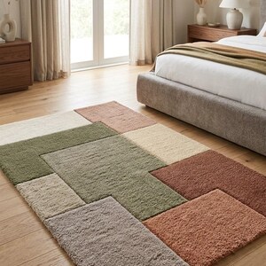 May include: A rectangular area rug featuring a geometric pattern of textured, shaggy blocks in shades of sage green, terracotta, cream, and taupe. The rug is composed of various rectangular sections with a high-pile, soft surface texture.