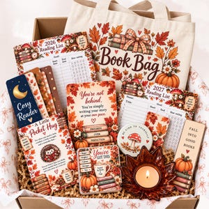 May include: A gift box containing a canvas tote bag with autumn leaf graphics, 2026 and 2027 reading list trackers, bookmarks with text like Cosy Reader and Fall Into Good Books, a Pocket Hug card, a You Got This coaster, and a leaf-shaped candle holder.