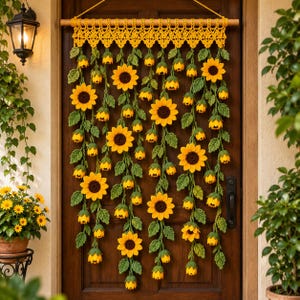 Può includere: Un arazzo all'uncinetto con molteplici fili di girasoli gialli con centri marrone scuro e foglie verdi, sospeso a un'asta di legno orizzontale con un bordo in pizzo all'uncinetto giallo e un cordino giallo per appenderlo.