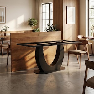 May include: A dining table base featuring a matte black metal frame with a distinctive U-shaped central support and an oval floor plate. The rectangular top frame is open, designed to hold a tabletop, and is positioned in front of a wood panel.