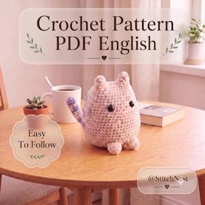 以下が含まれることがあります： かぎ針編みのパターンPDF English。分かりやすく、暗い目、小さなピンクの鼻、紫色の尾の先を持つ、小さくて丸い薄ピンク色の編みぐるみの猫が特徴です。Crochet Pattern PDF Englishと@StitchNestというテキストが表示されています。