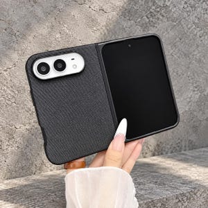 Könnte beinhalten: Eine schwarze, texturierte Smartphone-Hülle mit stoffartiger Oberfläche und einem markanten weißen Kameraausschnitt für zwei kreisförmige Linsen und einen Blitz, passend für ein faltbares Mobilgerät mit schwarzem Display.