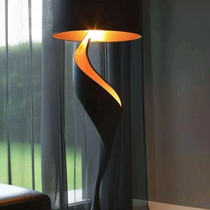 Op de afbeelding: Een vloerlamp met een matzwarte, spiraalvormige, organisch gevormde voet die naar boven buigt om een cilindrische zwarte lampenkap te ondersteunen. De binnenkant van de kap en de spiraalvormige uitsparing van de voet hebben een gouden afwerking.