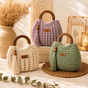 May include: Three crochet handbags in cream, lavender, and sage green, each featuring a round dark wood handle, a matching yarn tassel with a wooden bead, and a small rectangular leather-like patch with a floral design on the front.