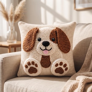 May include: A square crochet throw pillow featuring a cream-colored base with a three-dimensional dog design. The dog has brown floppy ears, black button eyes, a black nose, a small pink tongue, and two front paws with brown paw pads.