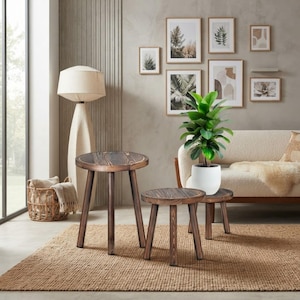 May include: A set of three round wooden stools with a dark brown stained finish and visible wood grain. Each stool features three sturdy, angled legs and a circular top. The stools are arranged in a cluster, varying in height, on a textured rug.