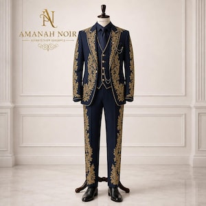 Puede incluir: Un traje de tres piezas azul marino con intrincados bordados florales dorados en las solapas de la chaqueta, el chaleco y las perneras del pantalón. Incluye corbata a juego, cadena de bolsillo dorada y zapatos negros. Texto: AMANAH NOIR.