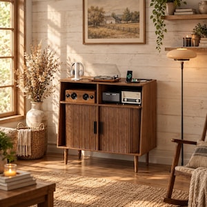 May include: A medium-brown wooden media console featuring two fluted cabinet doors with black vertical handles, an open upper shelf containing a record player, speakers, and a charging station, all supported by four tapered wooden legs.