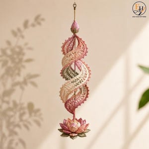 May include: A hanging crochet spiral ornament featuring a gradient of pink, cream, and sage green yarn. The structure consists of a central vertical axis with a lotus flower at the base and a small bud at the top, showcasing intricate lace patterns.
