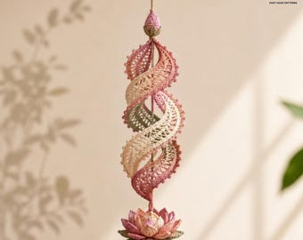 May include: A hanging crochet spiral ornament featuring a gradient of pink, cream, and sage green yarn. The structure consists of a central vertical axis with a lotus flower at the base and a small bud at the top, showcasing intricate lace patterns.
