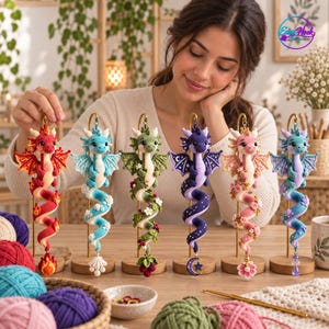 May include: Six crocheted dragon figurines displayed on individual gold metal stands. Each dragon features a unique theme: red with flames, light blue with shells, green with vines and berries, purple with stars, pink with flowers, and teal with crystals.
