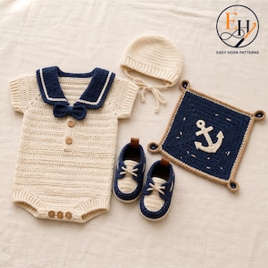 May include: A cream and navy blue crochet baby outfit set including a short-sleeve romper with a sailor collar and bow, a matching bonnet with ties, a pair of boat shoes with laces, and a square navy blue blanket featuring a white anchor design.