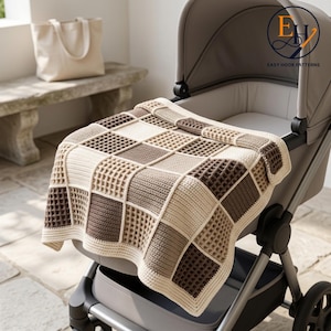 Peut inclure: Une couverture carrée au crochet présentant un motif de point gaufré dans un design à carreaux de couleurs crème, brun clair et brun foncé. La couverture est posée sur une poussette grise. Le logo EH EASY HOOK PATTERNS est visible en haut à droite.