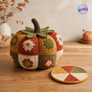 Puede incluir: Una calabaza de ganchillo hecha de cuadrados granny multicolores en tonos naranja, verde, crema y marrón, con un tallo marrón oscuro y hojas verdes. Al lado hay un posavasos circular de ganchillo con segmentos en forma de cuña.