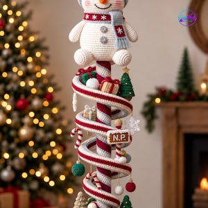 May include: A crochet snowman topper sits atop a spiral candy cane pole decorated with miniature crocheted ornaments including gift boxes, Christmas trees, candy canes, and baubles. A rectangular sign with the letters N.P. is attached to the pole.