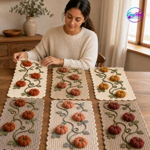 May include: Six rectangular crochet table runners featuring a scalloped edge and a repeating vine pattern with three-dimensional pumpkins in shades of orange, rust, and mustard yellow. The runners are displayed on a wooden table surface.