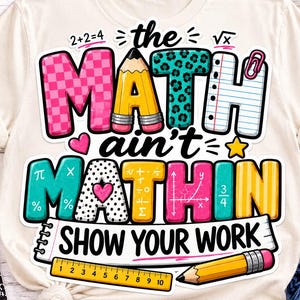 May include: A cream-colored t-shirt featuring a colorful graphic with the text "the MATH ain't MATHIN SHOW YOUR WORK". The design includes a yellow pencil, a ruler, mathematical symbols, and various patterns like checkers and leopard print.
