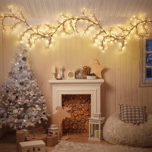 May include: A long, flexible brown branch garland featuring numerous small, warm white LED lights. The garland is draped horizontally across the top of a wall, creating a glowing, tree-like silhouette with many thin, branching twigs.